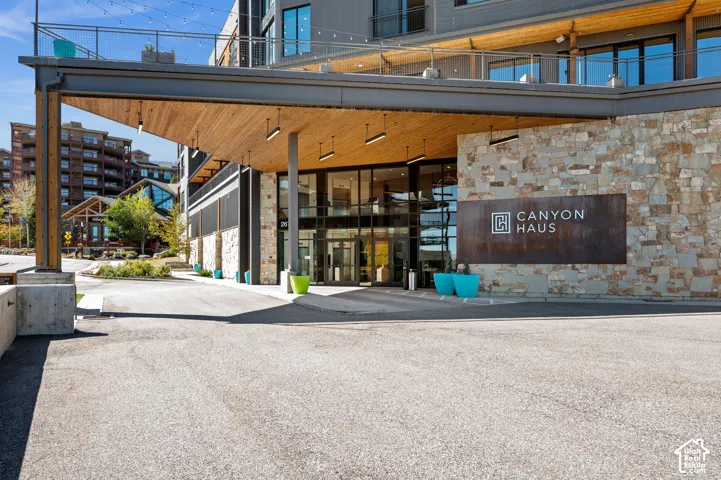 Building entrance featuring a stone facade, wood-finish overhang, and large glass doors
