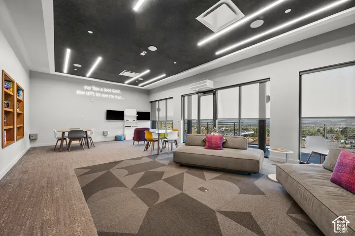 Recessed lighting and linear fixtures illuminate a carpeted common area with a geometric pattern