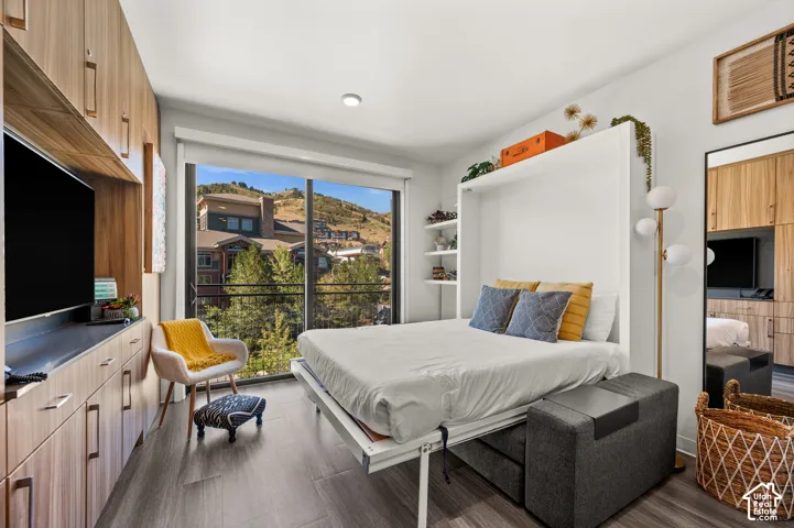 Integrated wall storage, floor-to-ceiling window, wood-finish flooring, built-in shelving, and a wall-mounted bed system