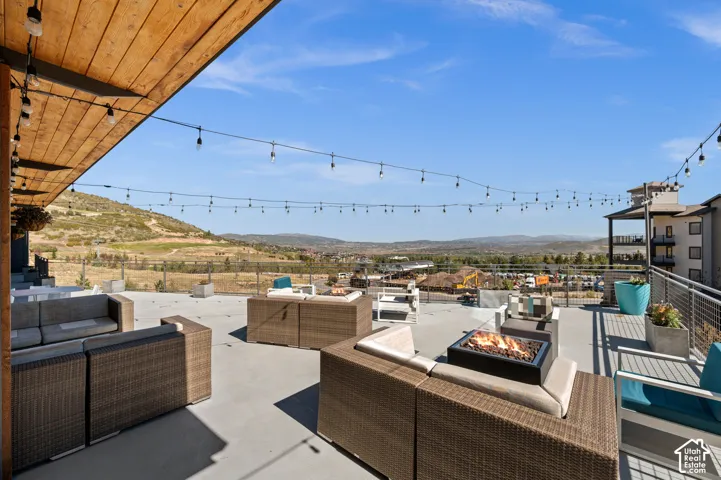 Expansive rooftop deck featuring a wood-panel ceiling, string lighting, and a built-in fire pit