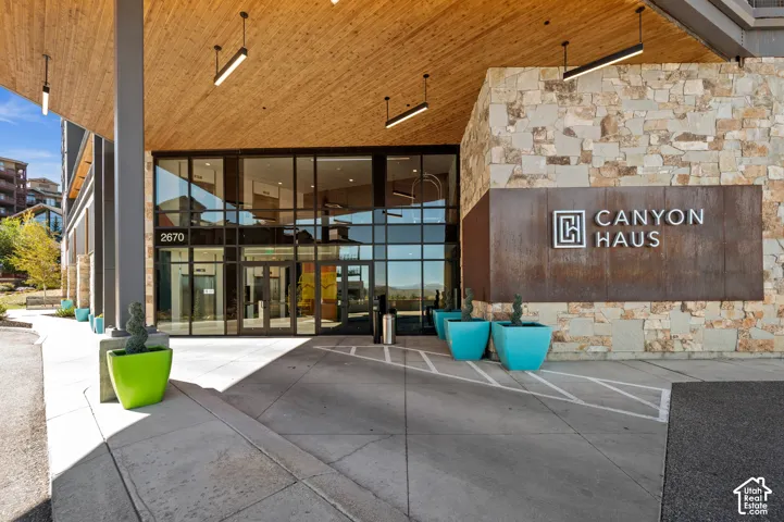 Building exterior featuring stone cladding, large glass panels, a wood-finish ceiling, and a prominent building sign