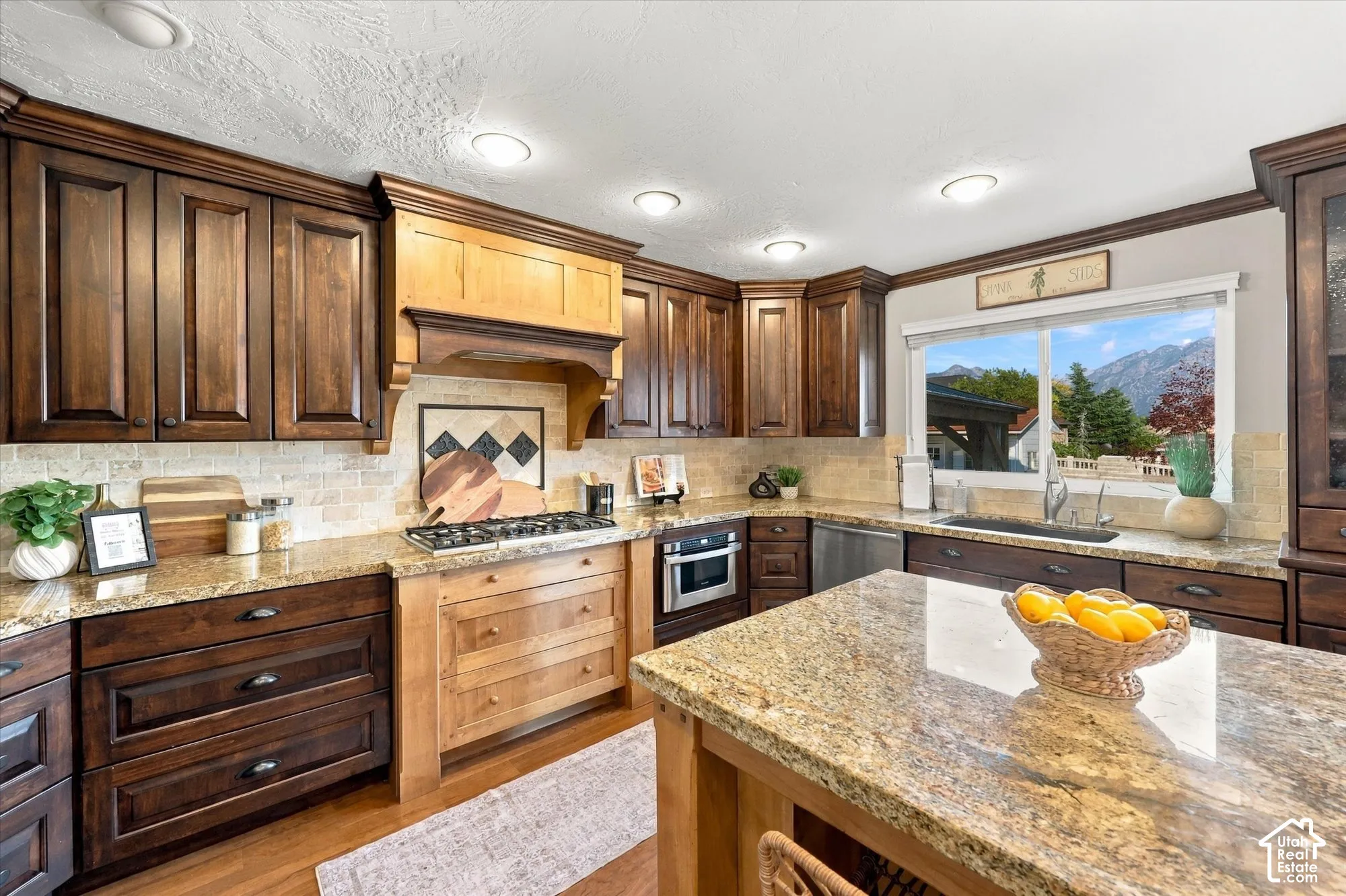 Kitchen featuring rich wood cabinetry, stone countertops, a tiled backsplash, stainless steel appliances, and recessed lighting