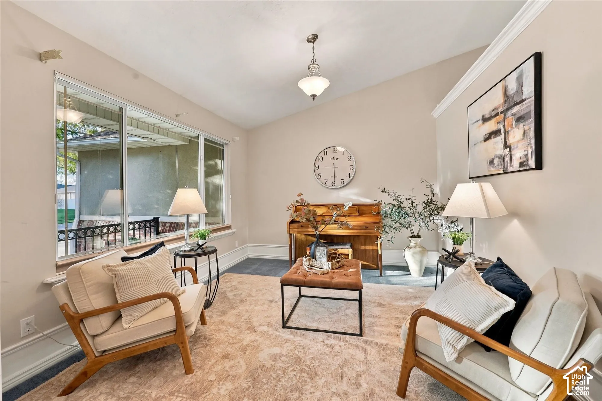 Vaulted ceiling with crown molding and a central pendant light fixture