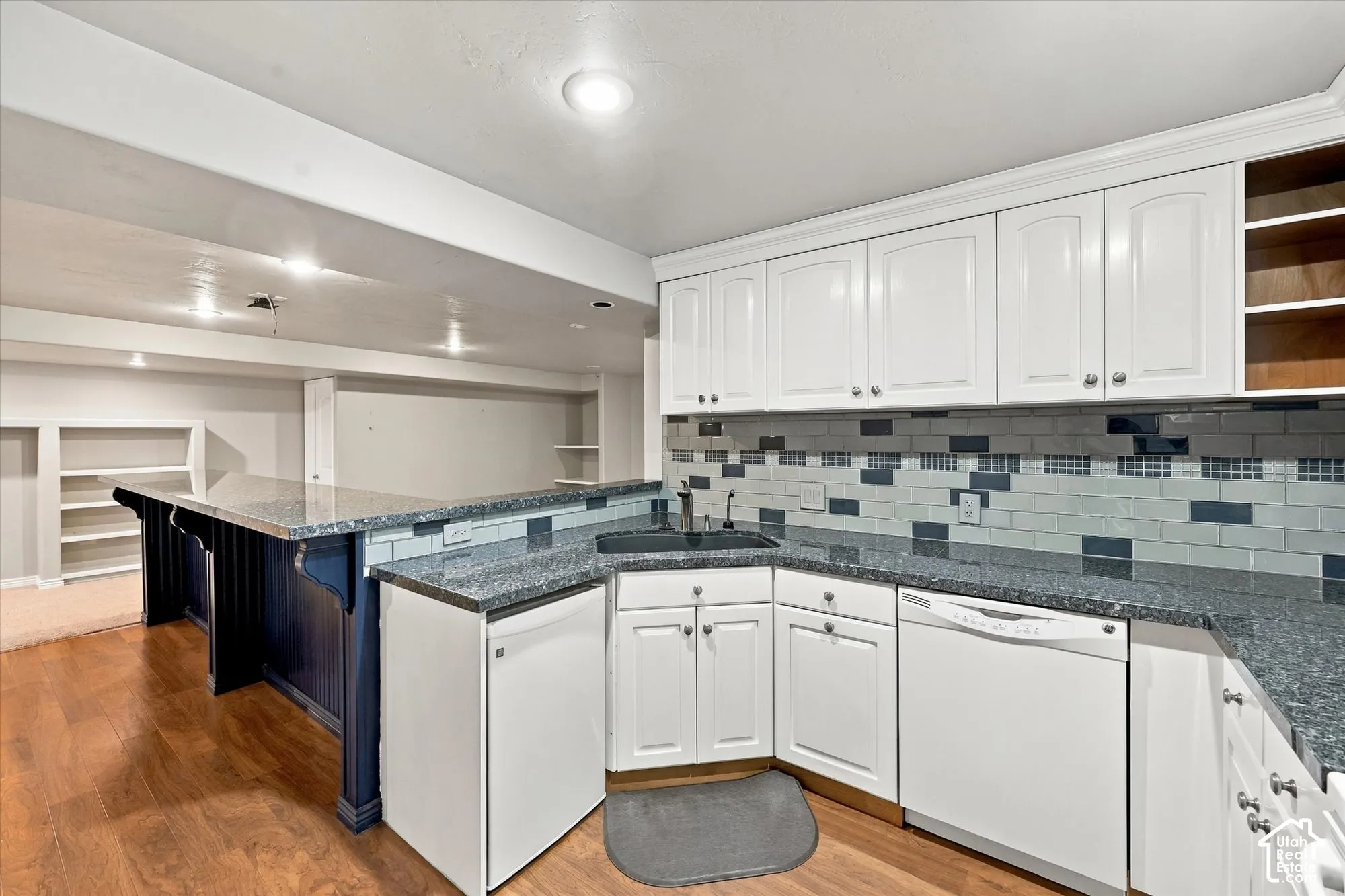 Contemporary kitchen featuring white cabinetry, stainless steel appliances, and a multi-toned subway tile backsplash