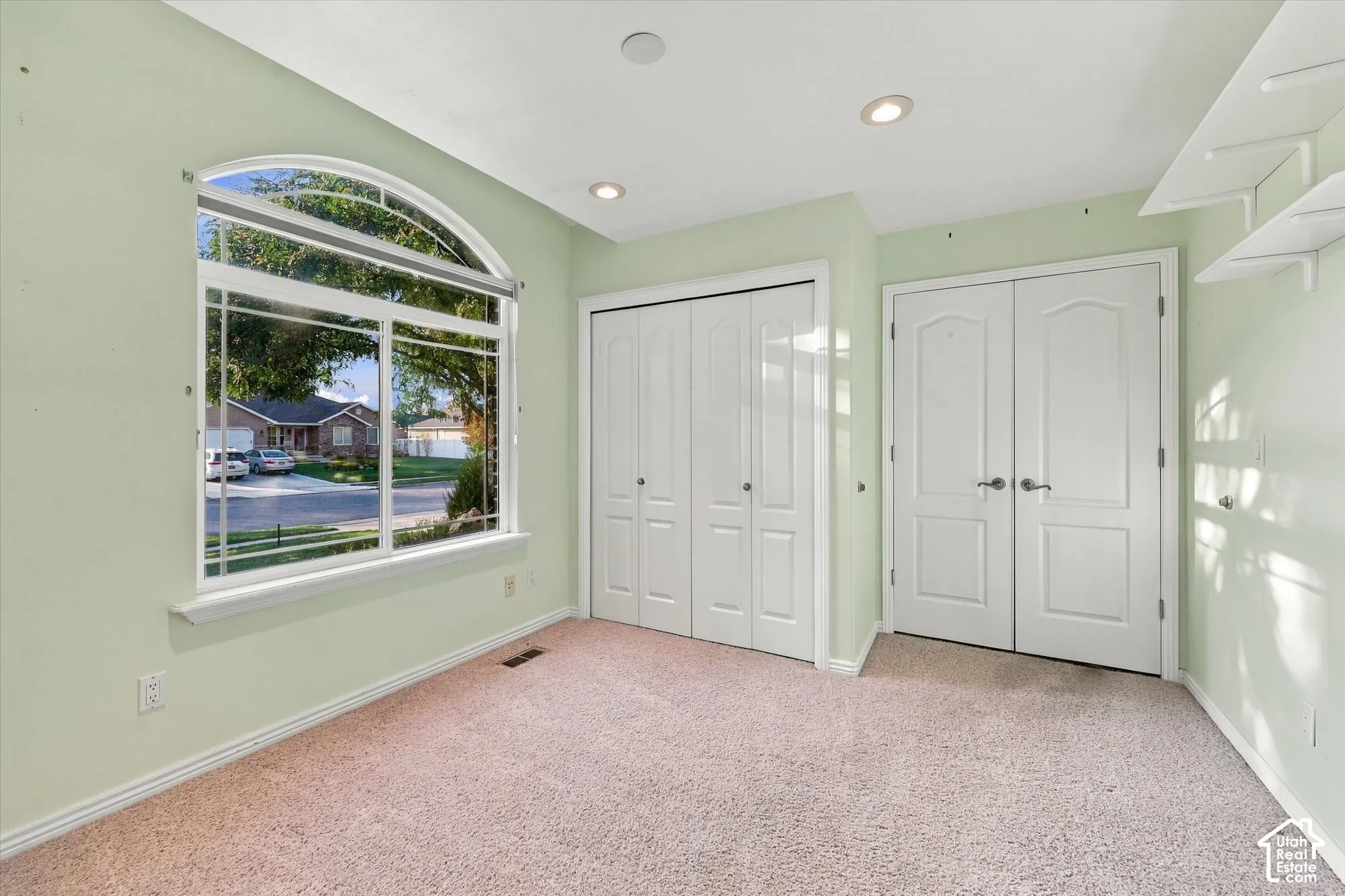 Arched window, recessed lighting, carpet flooring, bi-fold closet doors, and double panel doors