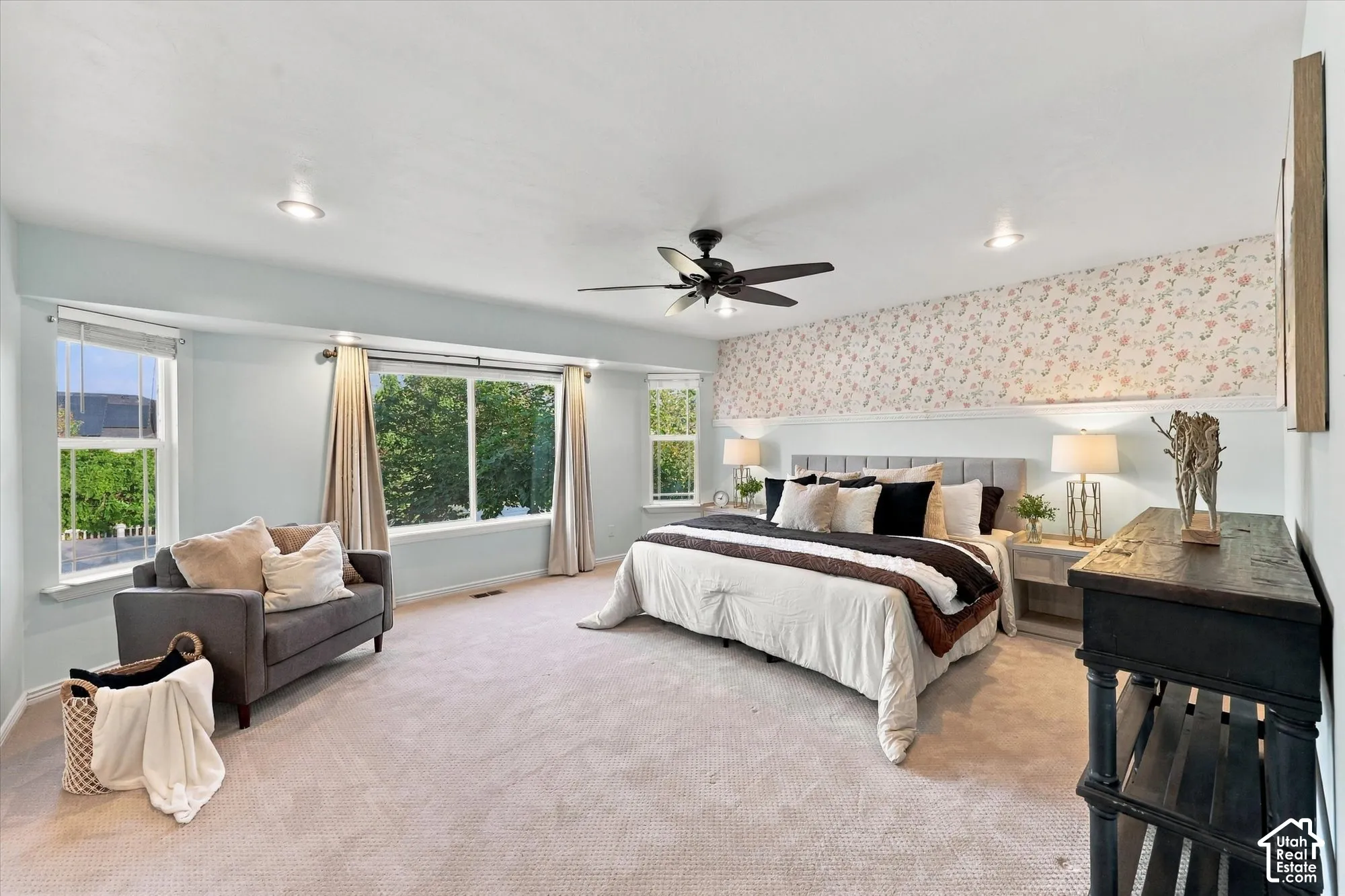 Recessed lighting with a ceiling fan, light-colored carpeting, multiple windows, and a decorative wall feature