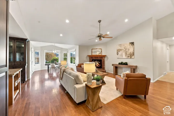 Vaulted ceilings, recessed lighting, wood-finish flooring, brick-faced fireplace with wood mantel, and built-in cabinetry