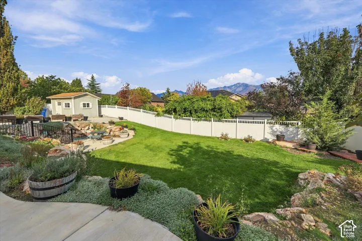 Expansive backyard featuring a lush lawn, concrete patio, and garden shed