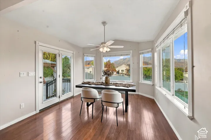 Hardwood-finish flooring, French doors with exterior railing, ceiling fan with light fixture, multiple large windows, and a bay window feature in this space