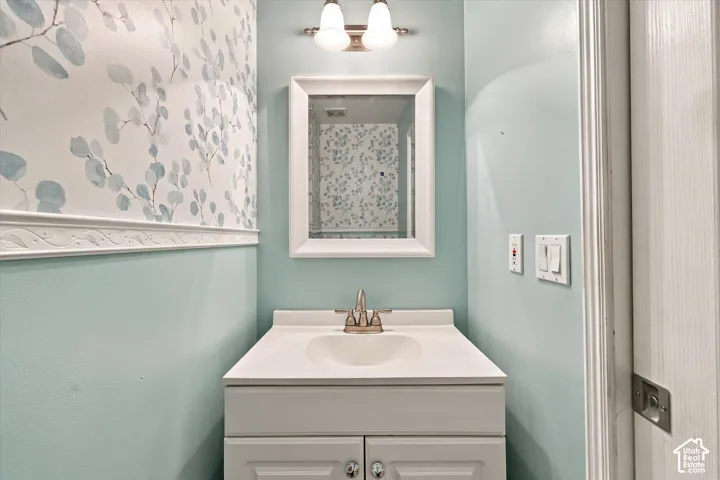Bathroom vanity with integrated sink, brushed nickel faucet, wall-mounted mirror, and decorative wall paneling