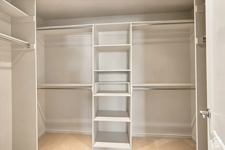 Spacious walk-in closet featuring dual hanging rods with multiple shelving sections, a center tower with built-in shelves for organized storage, and wood-finish flooring throughout