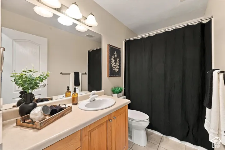 Bathroom featuring a light wood-finish vanity, a spacious countertop, a large wall-mounted mirror, and a white toilet