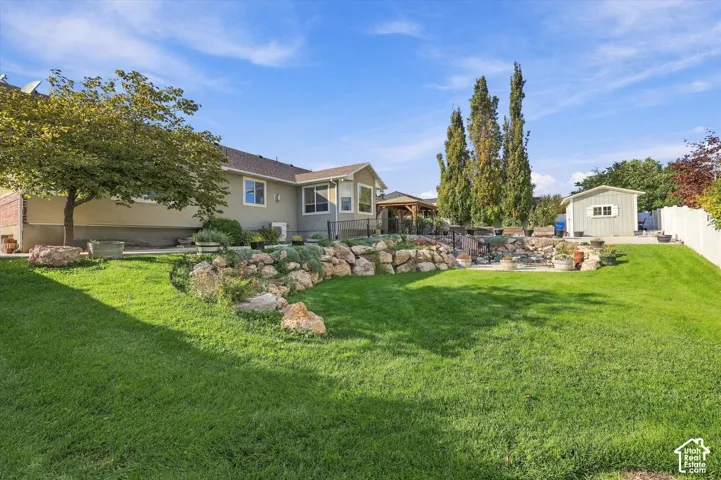 Expansive backyard featuring a manicured lawn, established rock landscaping, and mature trees