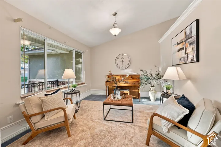 Vaulted ceiling with crown molding and a central pendant light fixture