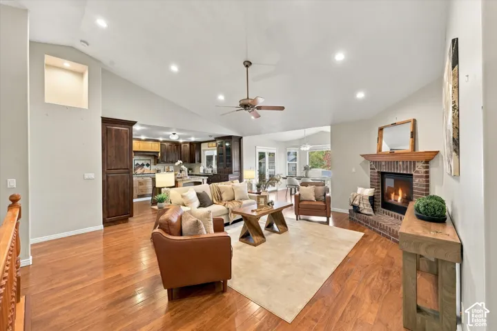 Vaulted ceilings, recessed lighting, wood-finish flooring, brick fireplace with wood mantel, and a ceiling fan