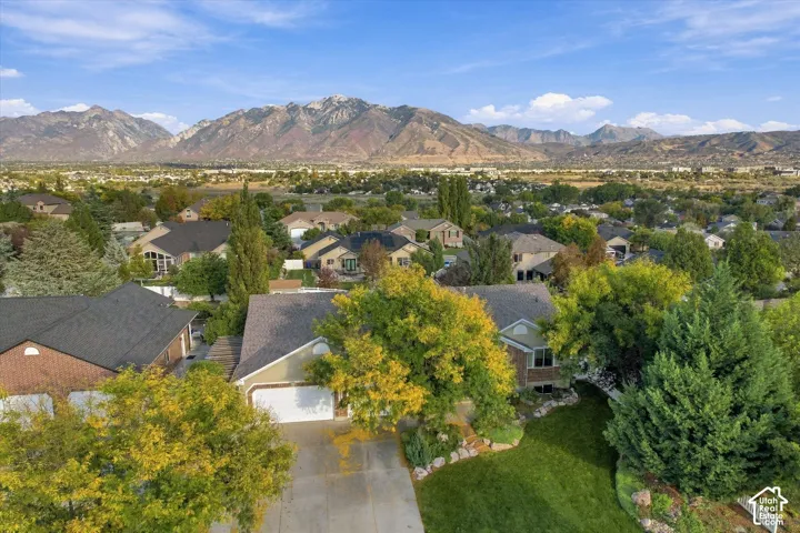 Prestigious residential community nestled against mountain backdrop, featuring tree-lined streets, manicured lawns, and established landscaping throughout the neighborhood