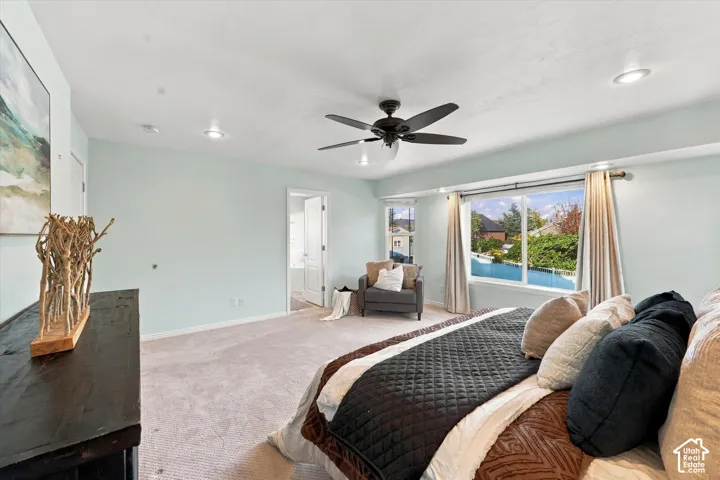 Wall-to-wall carpeted flooring, recessed lighting, ceiling fan, wide window, and a white interior door