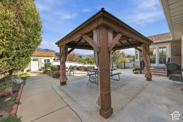 Covered timber pavilion with exposed beam construction and substantial wood posts anchoring a generous concrete patio