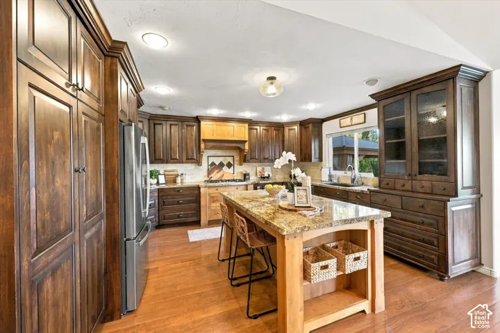 Wood-finish flooring, recessed lighting, and a large central island with seating