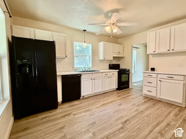 Wood-finish flooring throughout, white cabinetry with dark hardware, white subway tile backsplash, ceiling fan with light, and recessed lighting