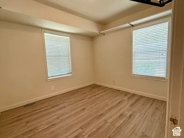 Wood-finish flooring with white trim, two windows, and neutral wall tones