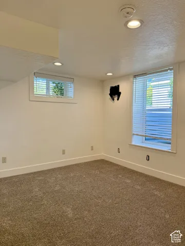 Recessed lighting, light-colored walls, brown carpet flooring, and white window blinds