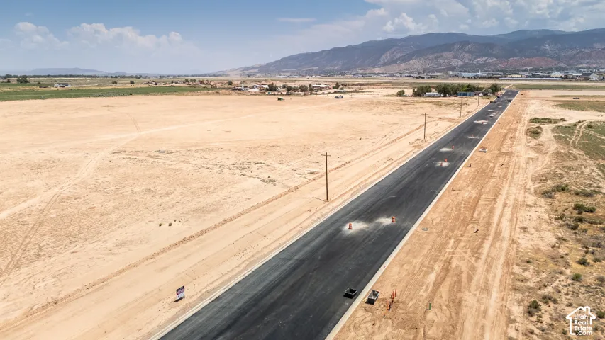 Expansive undeveloped land featuring a newly paved road and distant mountain scenery