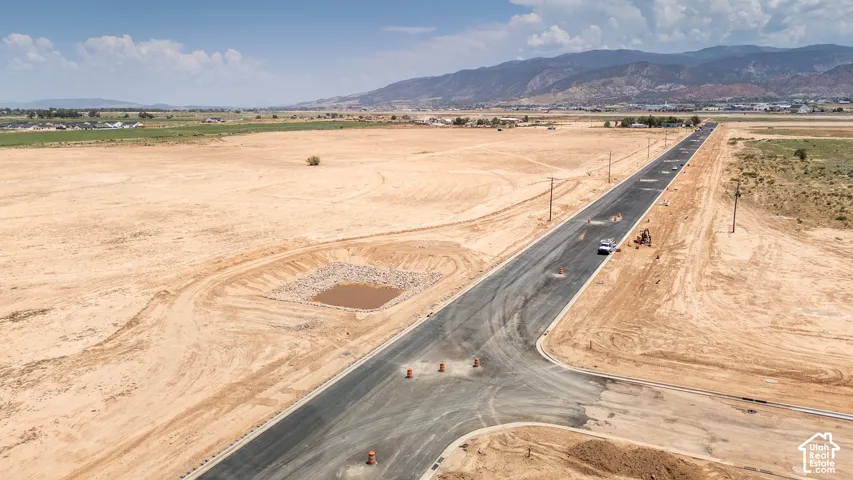 Paved road infrastructure, raw land parcels, and mountain backdrop