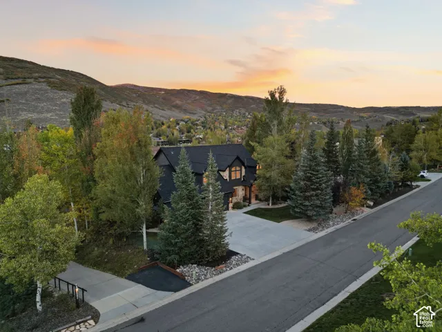 Expansive property with a dark-clad exterior, stone accents, multiple large windows, and a dark shingle roof