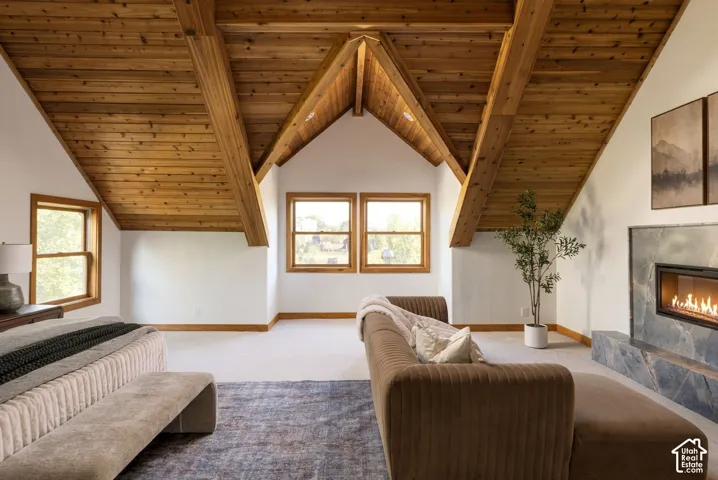 Vaulted wood-plank ceiling with exposed beams, multiple double-hung windows with wood trim, and a built-in linear fireplace with a stone surround