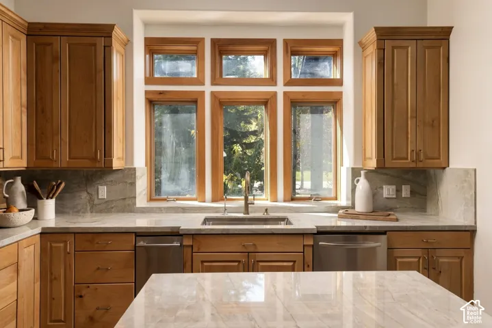 Light wood cabinetry, stainless steel sink, coordinated countertops with backsplash, and six paneled windows