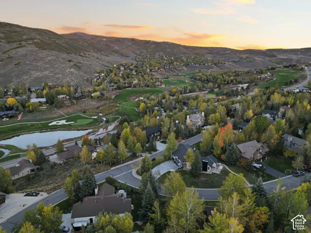 Mountain landscape with residential properties, surrounded by mature trees, a golf course, and a pond