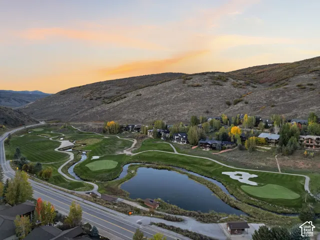 Aerial perspective showcasing a golf course, tranquil pond, and surrounding homes