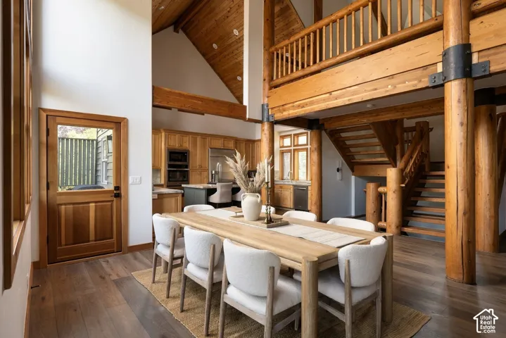 Vaulted wood-paneled ceiling, exposed timber beams, wood-finish flooring, wood cabinetry, and stainless steel appliances