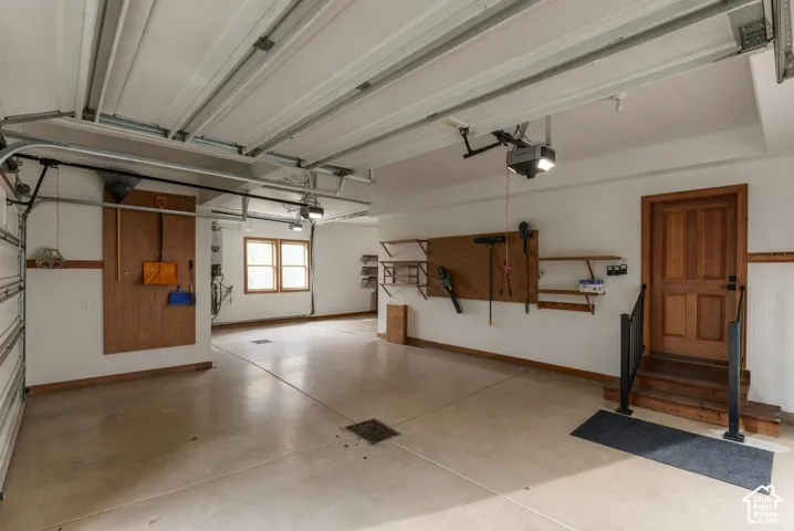 Spacious garage with concrete flooring, natural wood door, dual windows, and built-in shelving