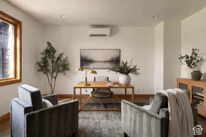 Recessed ceiling lighting, wood-finish flooring, wood window trim, mini-split air conditioning unit, and a built-in wood cabinet with glass panel doors
