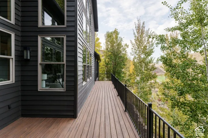 Elevated composite deck with horizontal board decking extends from the modern black-clad residence, featuring a black metal railing system