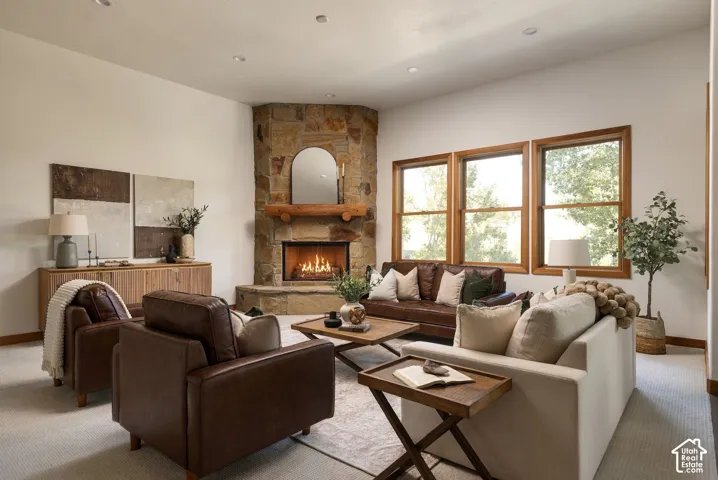 Stone-clad corner fireplace with a substantial wooden mantel, multiple large windows, and recessed ceiling lighting