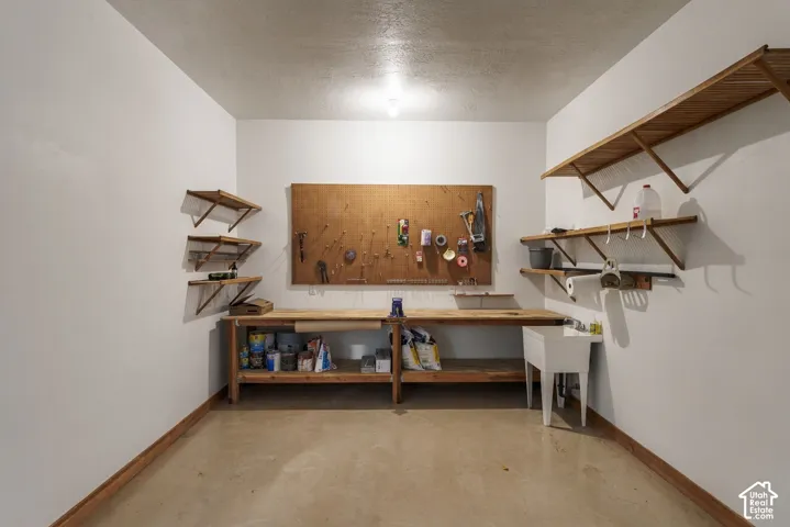 Utility room with a built-in workbench, wall-mounted shelving, a utility sink, and a pegboard