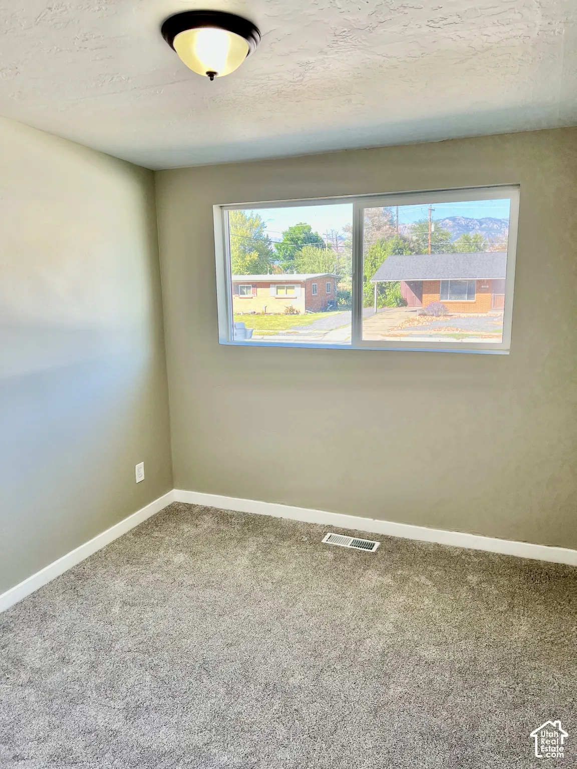 Room with neutral-toned walls, gray carpeting, and a dual-pane window