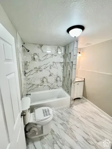 Tiled flooring, white vanity with stone-finish countertop, full bathtub, tiled shower surround, and flush-mounted ceiling light fixture