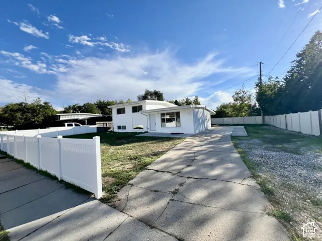 White exterior, privacy fencing, expansive driveway, established trees