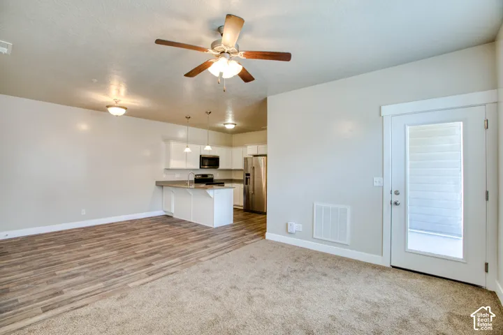 Open-concept living space with wood-finish flooring, recessed lighting, ceiling fan, and access to an outdoor area
