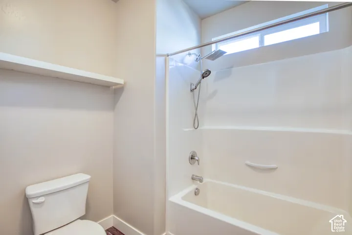White bathtub and shower combination with a fixed rain showerhead, handheld shower fixture, and a transom window