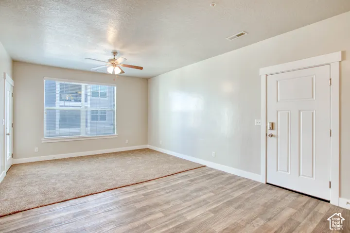 Wood-finish flooring, recessed lighting, ceiling fan, and large window with blinds