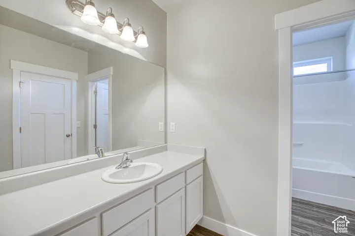 Vanity with a single basin sink, chrome faucet, and white cabinetry