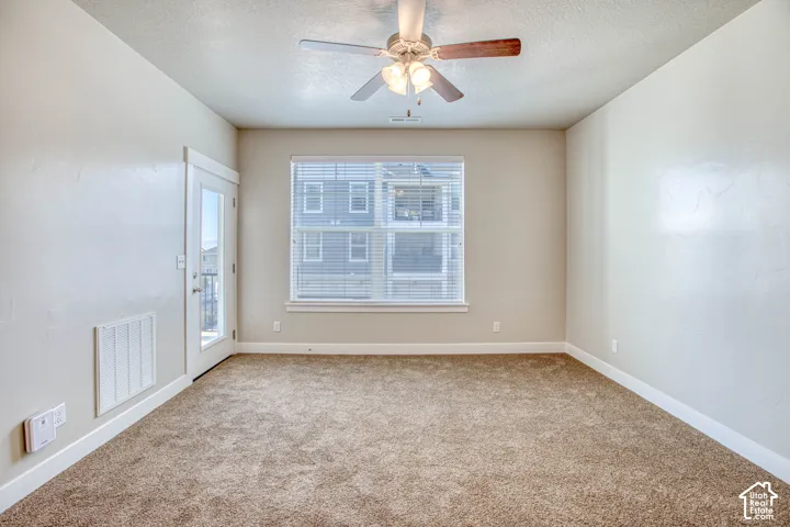 Light brown carpet flooring, ceiling fan with integrated lighting, window with blinds, and a glass-paneled door