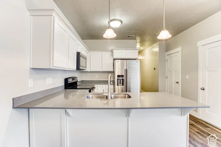 Kitchen island with an undermount double basin sink, stainless steel faucet, and light-toned countertops