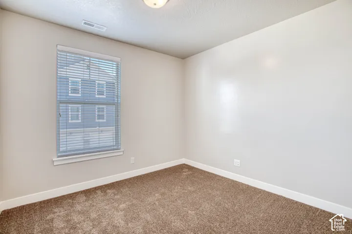 Carpeted flooring, neutral wall tones, window with horizontal blinds, and a flush mount ceiling light fixture