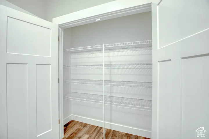 Walk-in pantry featuring white wire shelving, wood-finish flooring, and white trim